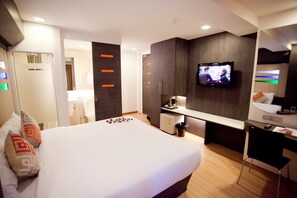 A modern hotel room with a large bed, a desk, a television, and a small kitchenette. - Studio Sukhumvit 11 (Bangkok)