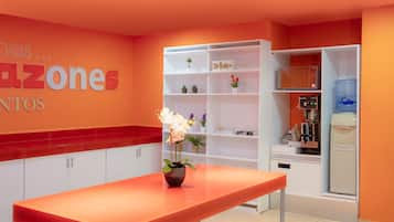 Una cocina moderna con armarios blancos, una encimera roja y una estantería blanca con diversos objetos.
