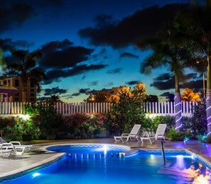 A swimming pool with lounge chairs and a fence, surrounded by palm trees and plants. - One Cancun Centro (Cancun)