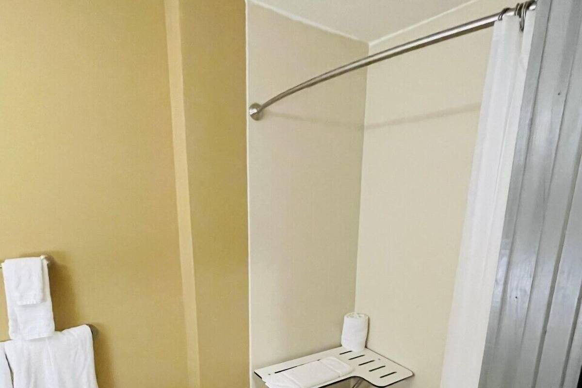 A bathroom with a shower, a towel rack, and a small shelf with toiletries.