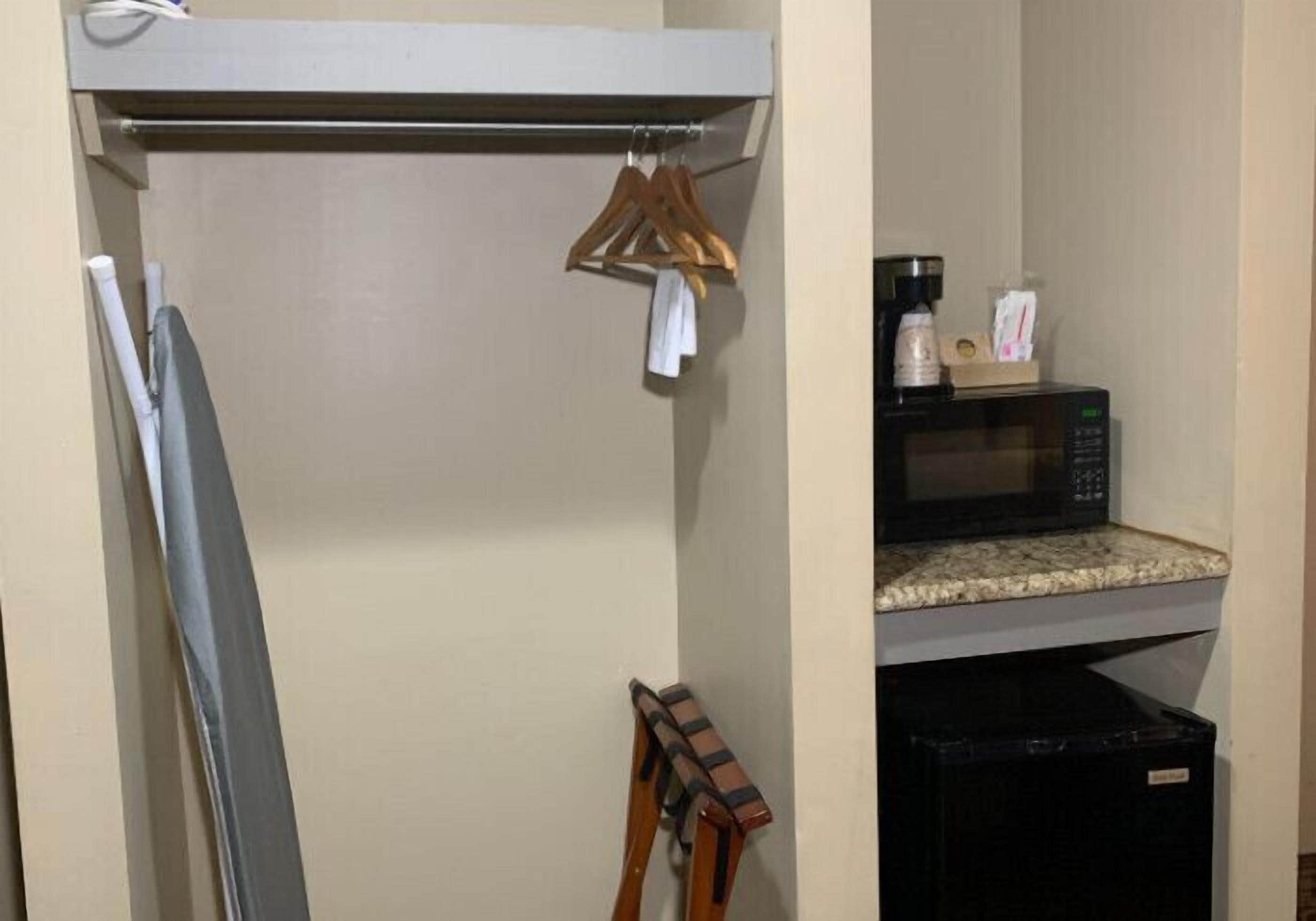 Una kitchenette con microondas, una pequeña encimera y un cubo de basura negro.