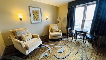 Habitación de hotel con dos sillones, una mesita y vistas de la ciudad a través de amplios ventanales.