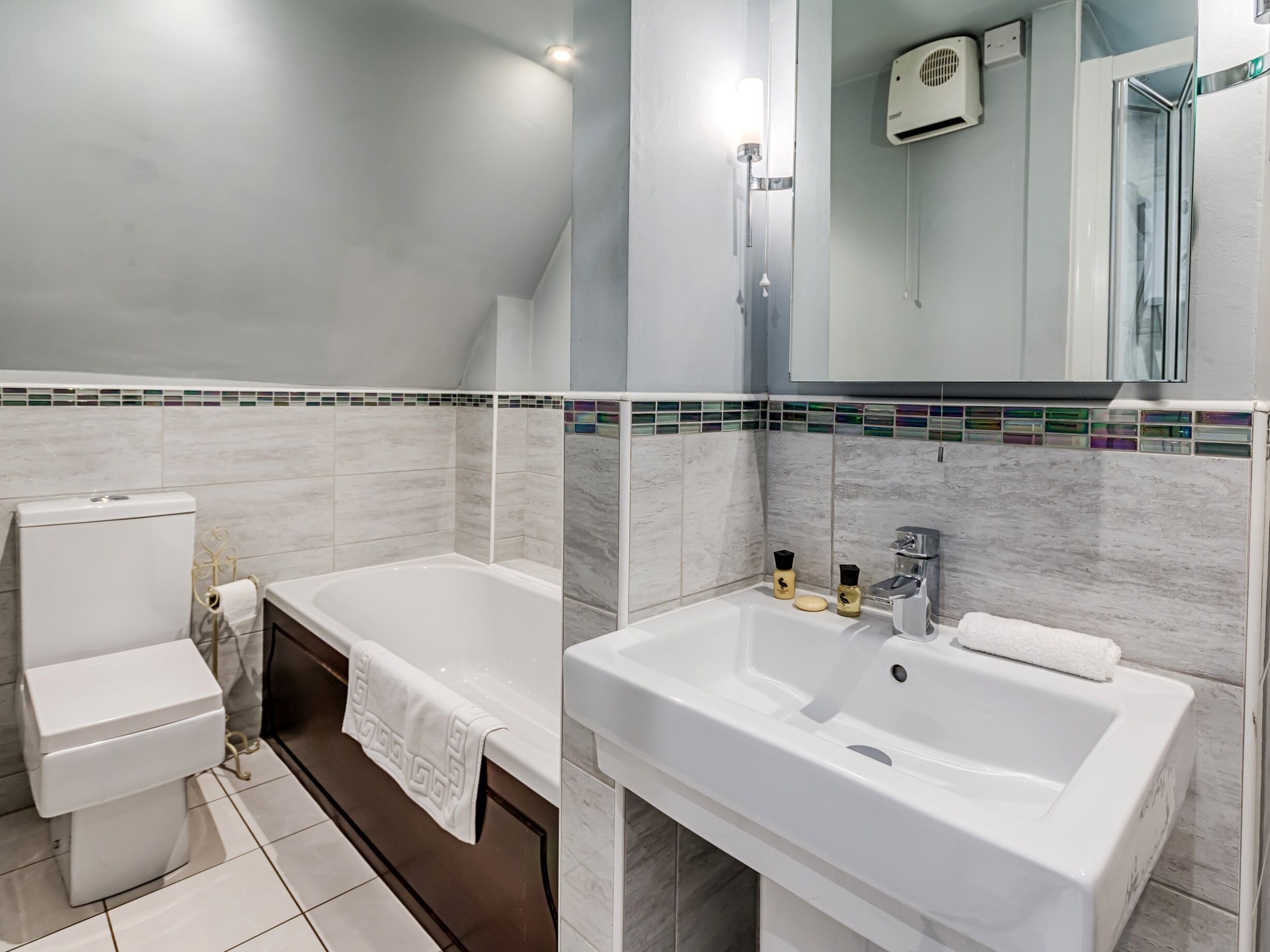 A modern bathroom with a toilet, bathtub, and sink.