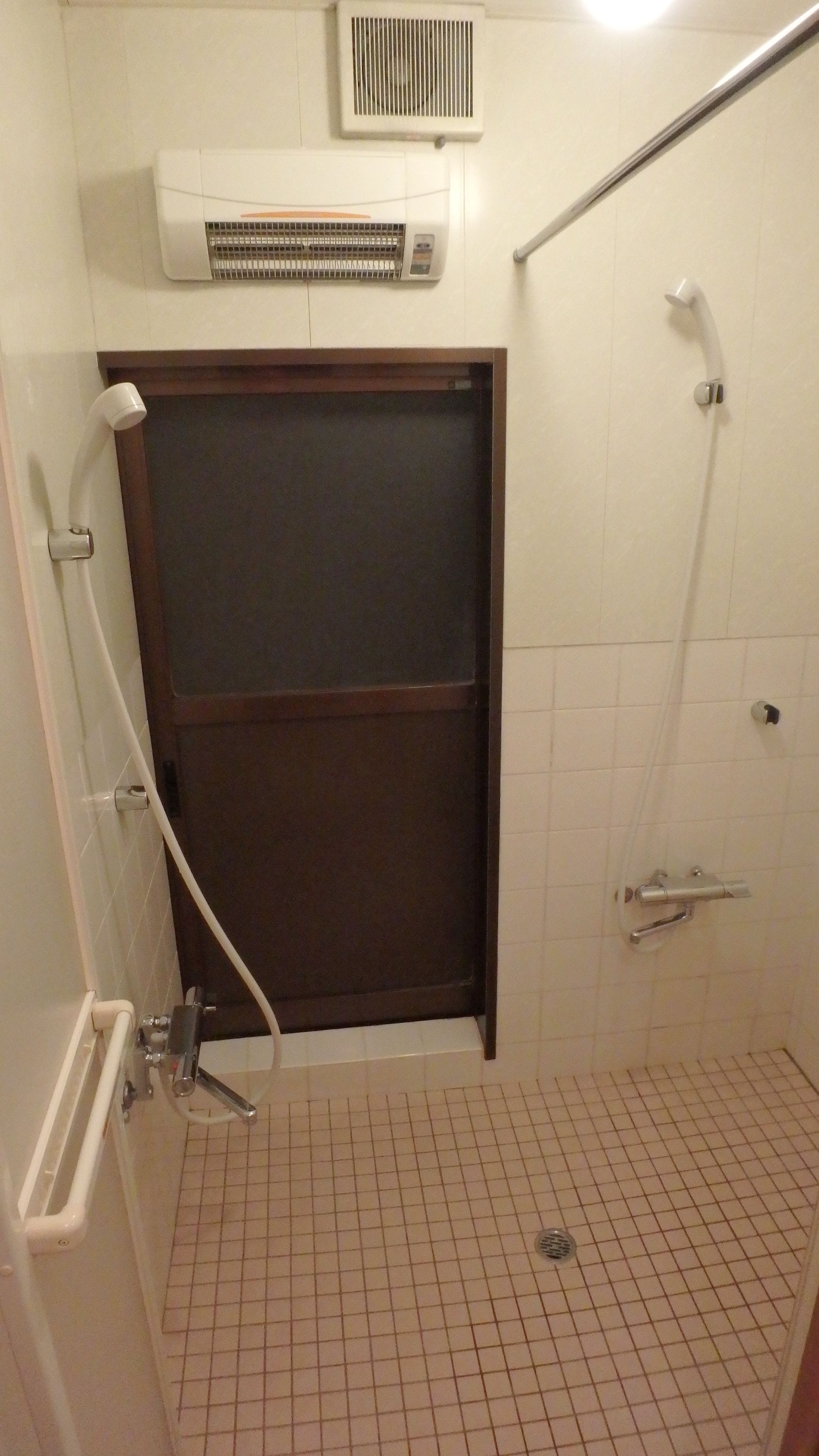 A small, tiled bathroom with a shower, a toilet, and a sink.