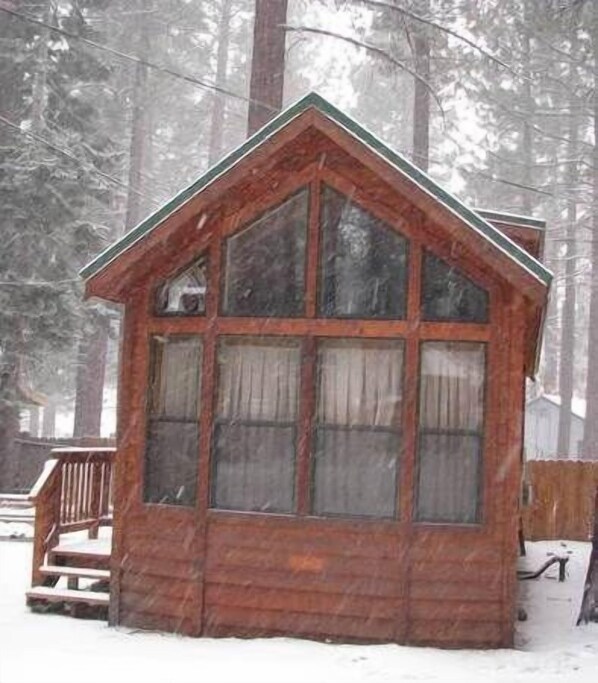 A wooden cabin with a steeply pitched roof and a large window.