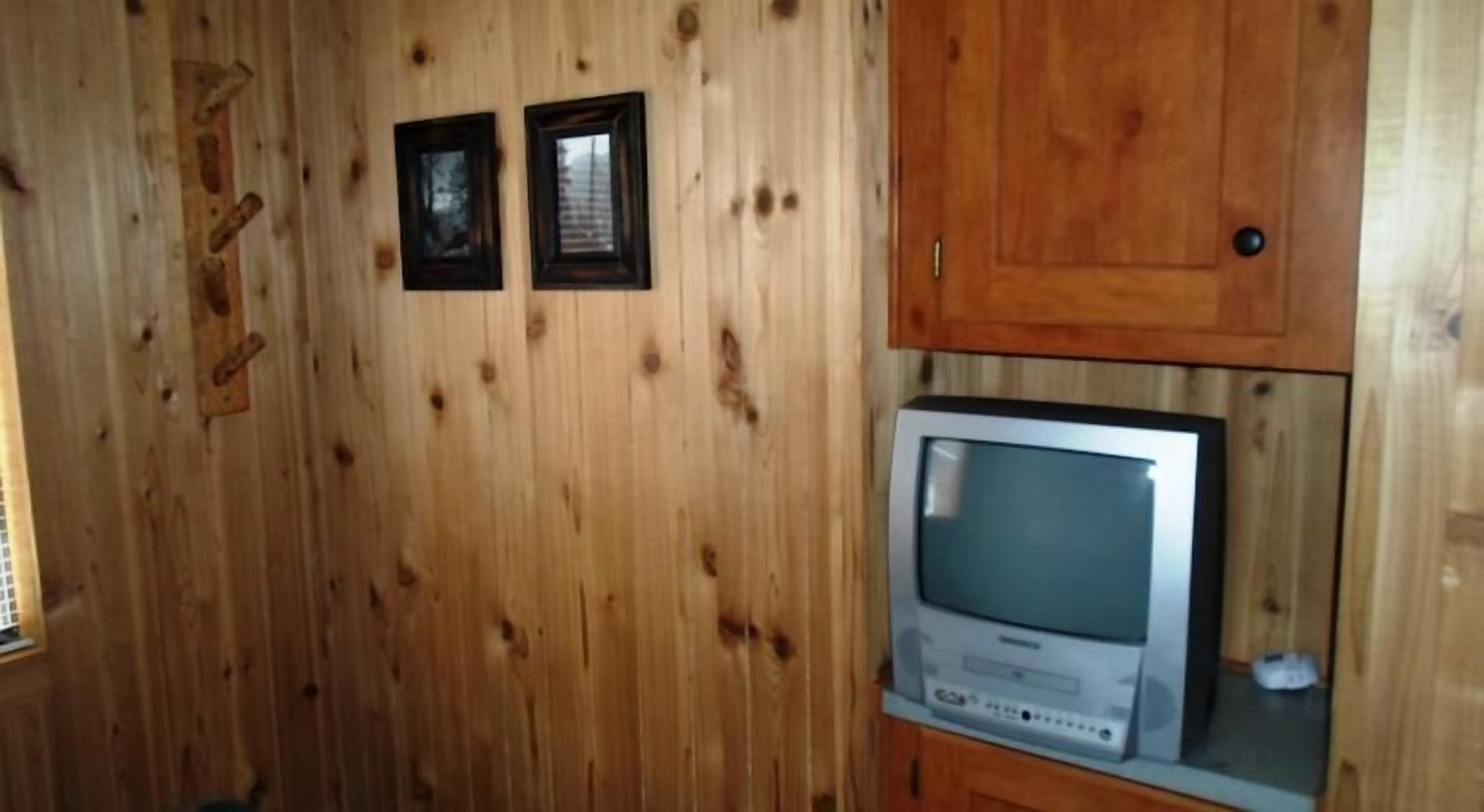 Une pièce aux murs lambrés, avec un téléviseur posé sur un meuble en bois.