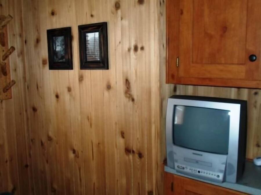 A wooden-paneled room with a television on a wooden stand.