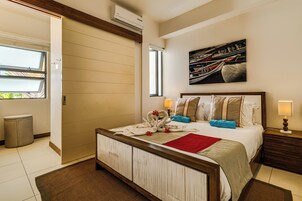 Una habitación de hotel con una cama, un cuadro, una ventana y un cesto de basura.