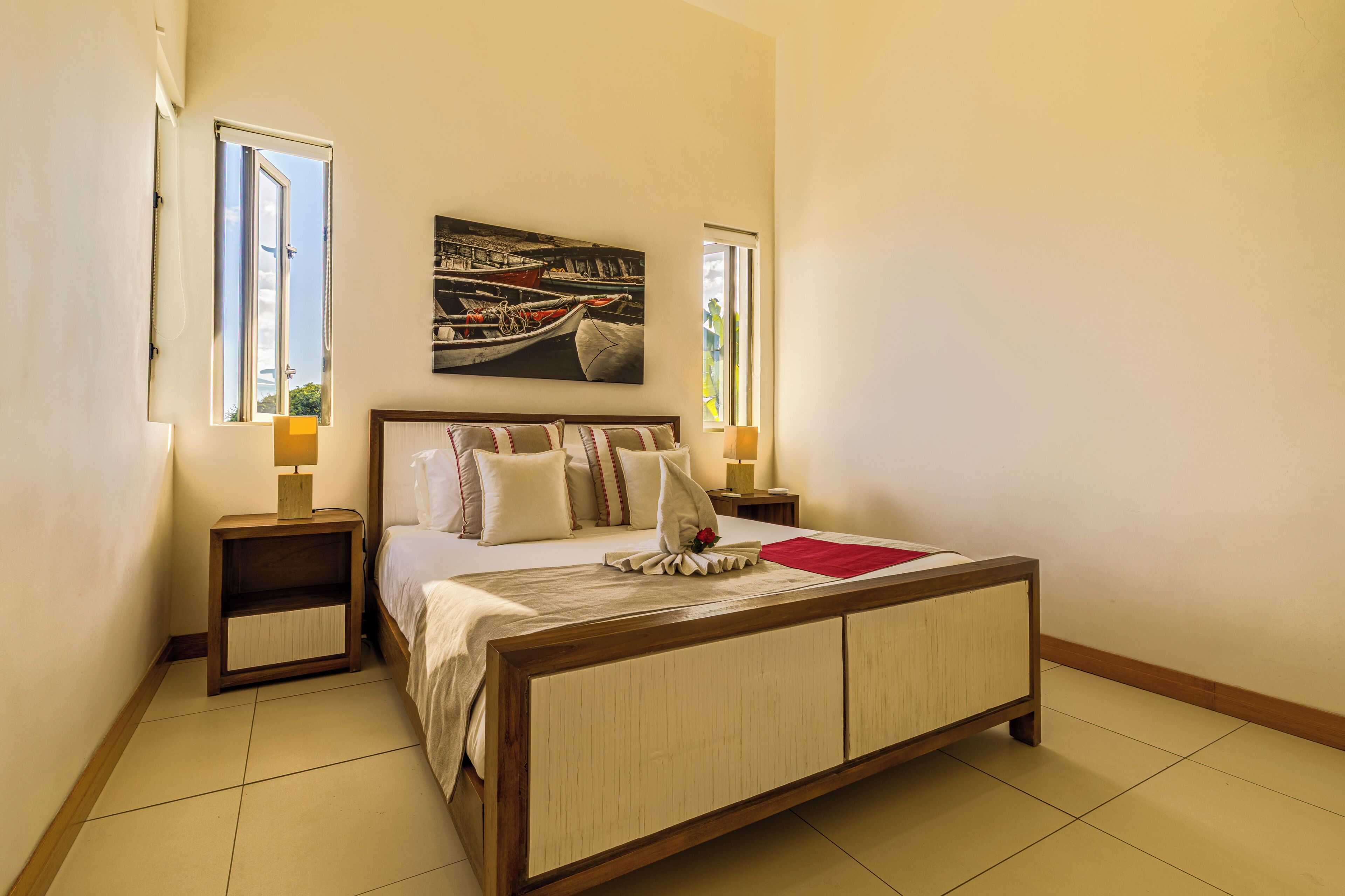 Une chambre à coucher avec un grand lit, deux tables de chevet, une commode, un tableau et une fenêtre.