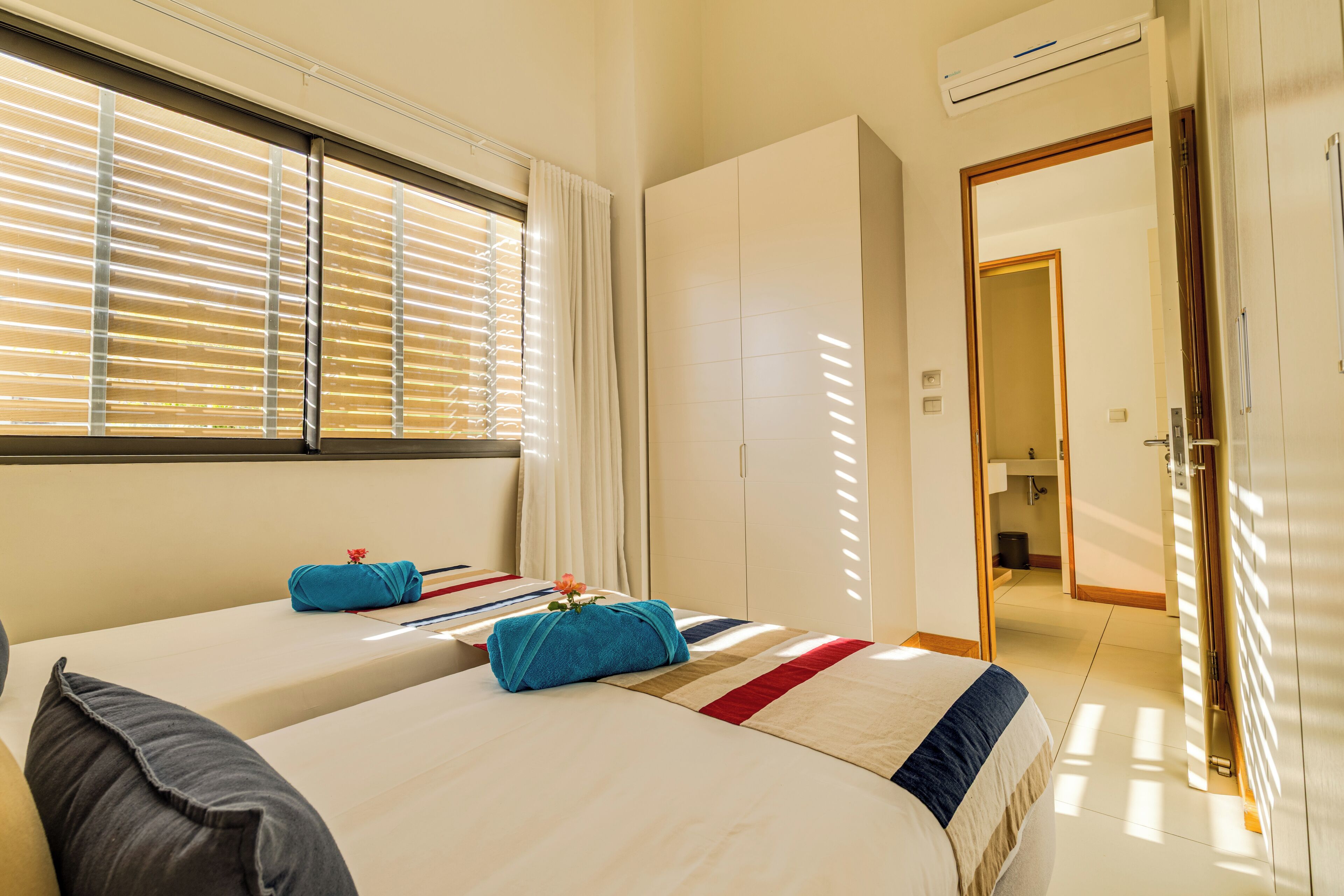 A hotel room with two beds, a bathroom, and a wardrobe.