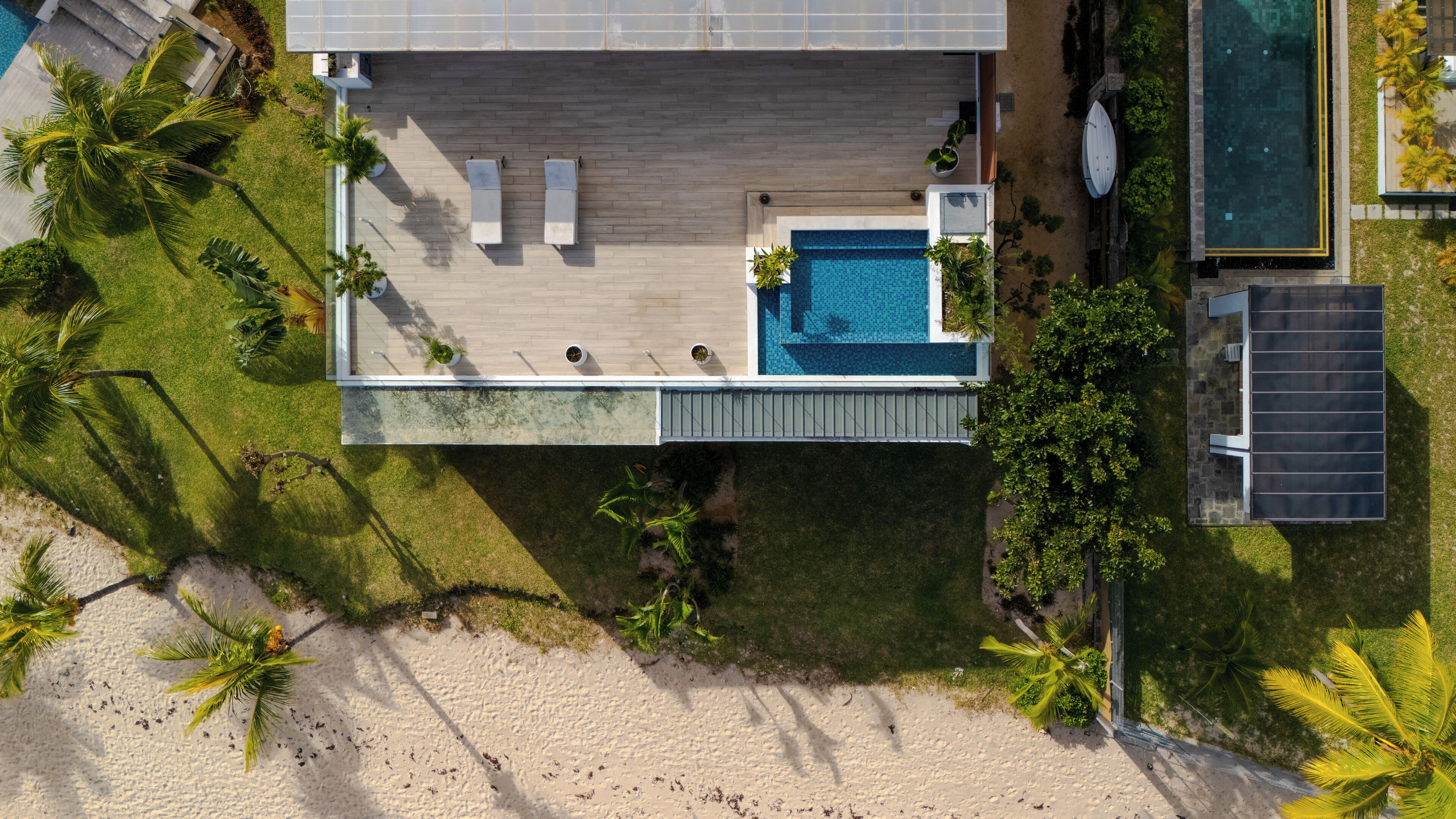 Vista aérea de una casa moderna con piscina, dos sillones de descanso y una pequeña zona de terraza.