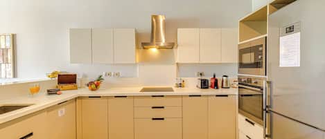 Una cocina moderna con armarios blancos, electrodomésticos de acero inoxidable y una isla central.
