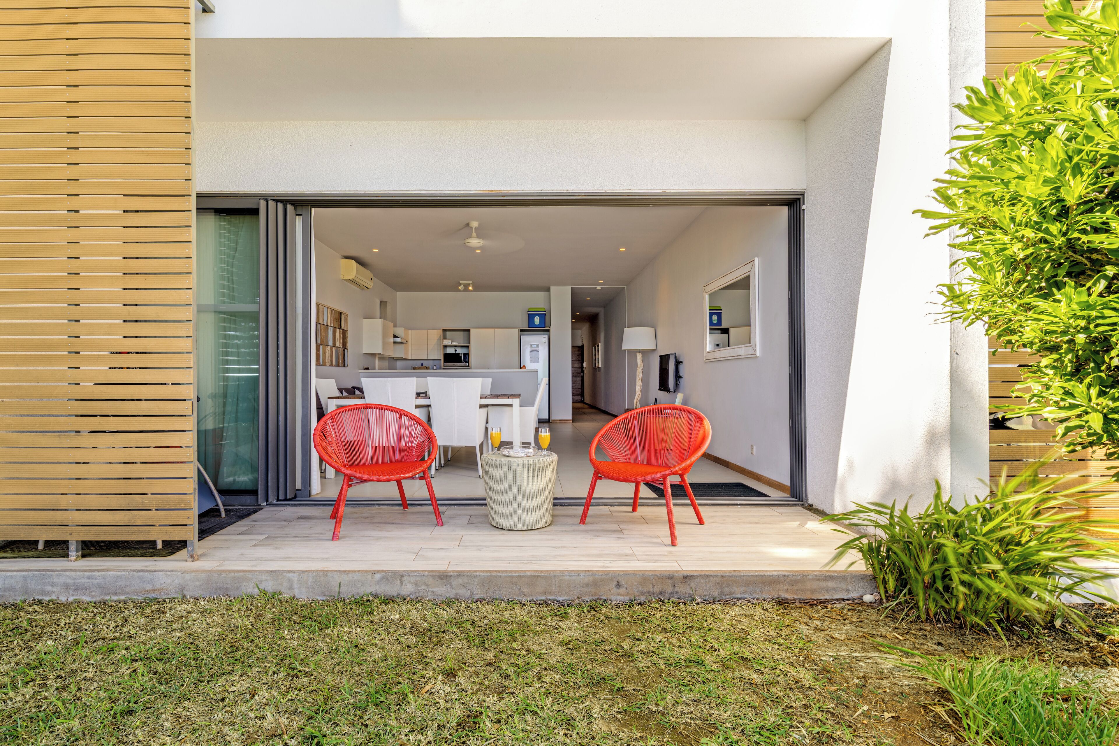 A modern house with a patio area featuring two red chairs and a small table.