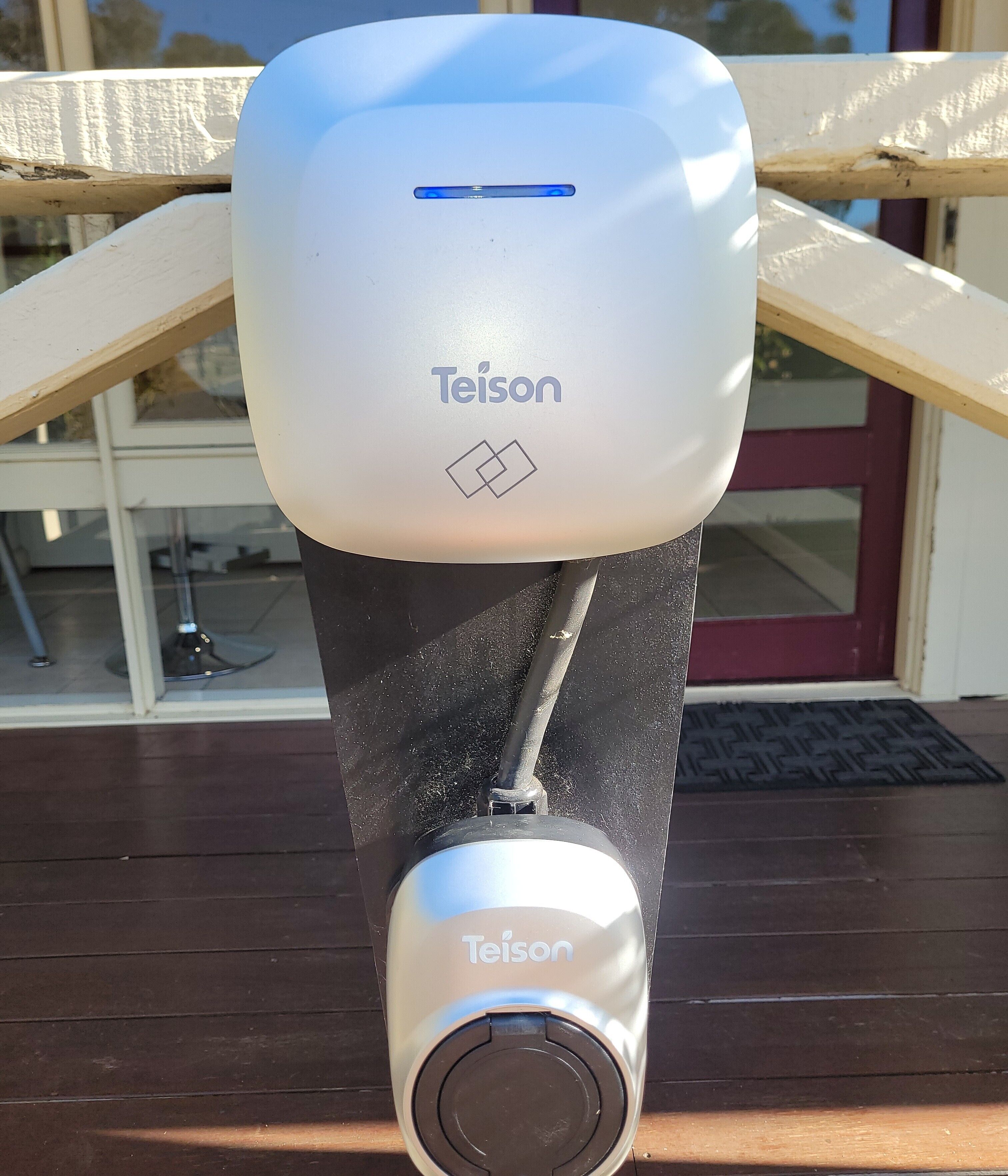 Un distributeur de gel hydroalcoolique de la marque Teison fixé sur une terrasse en bois.