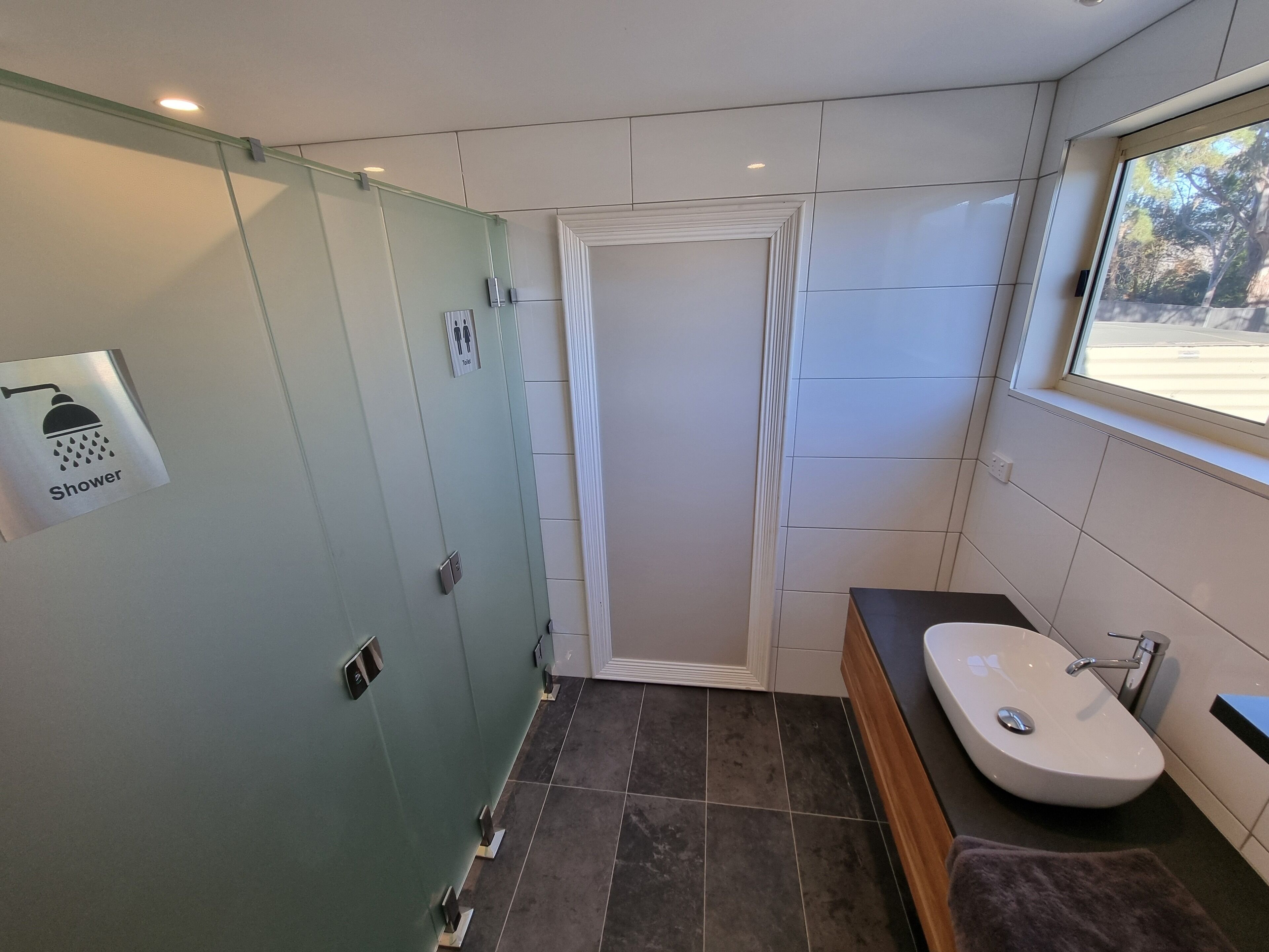 A modern bathroom with a glass shower enclosure, a vanity with a sink, and a window providing natural light.