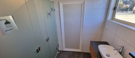 A modern bathroom with a glass shower enclosure, a vanity with a sink, and a window providing natural light.