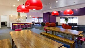 A modern office space with a wooden conference table, red chairs, and a purple accent wall.