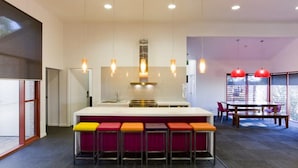A modern kitchen with a central island, bar stools, and pendant lighting.