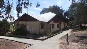 A two-story brick building with a metal roof, a small porch, and a flag on the front.