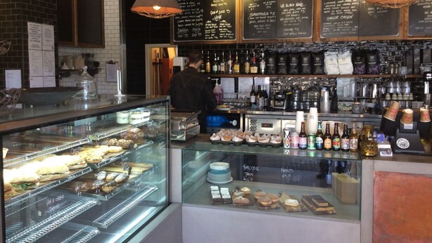 A bakery display case with pastries and a coffee bar area with various beverages and snacks.
