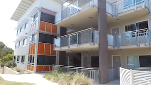 A multi-story residential building with balconies, large windows, and a flat roof.