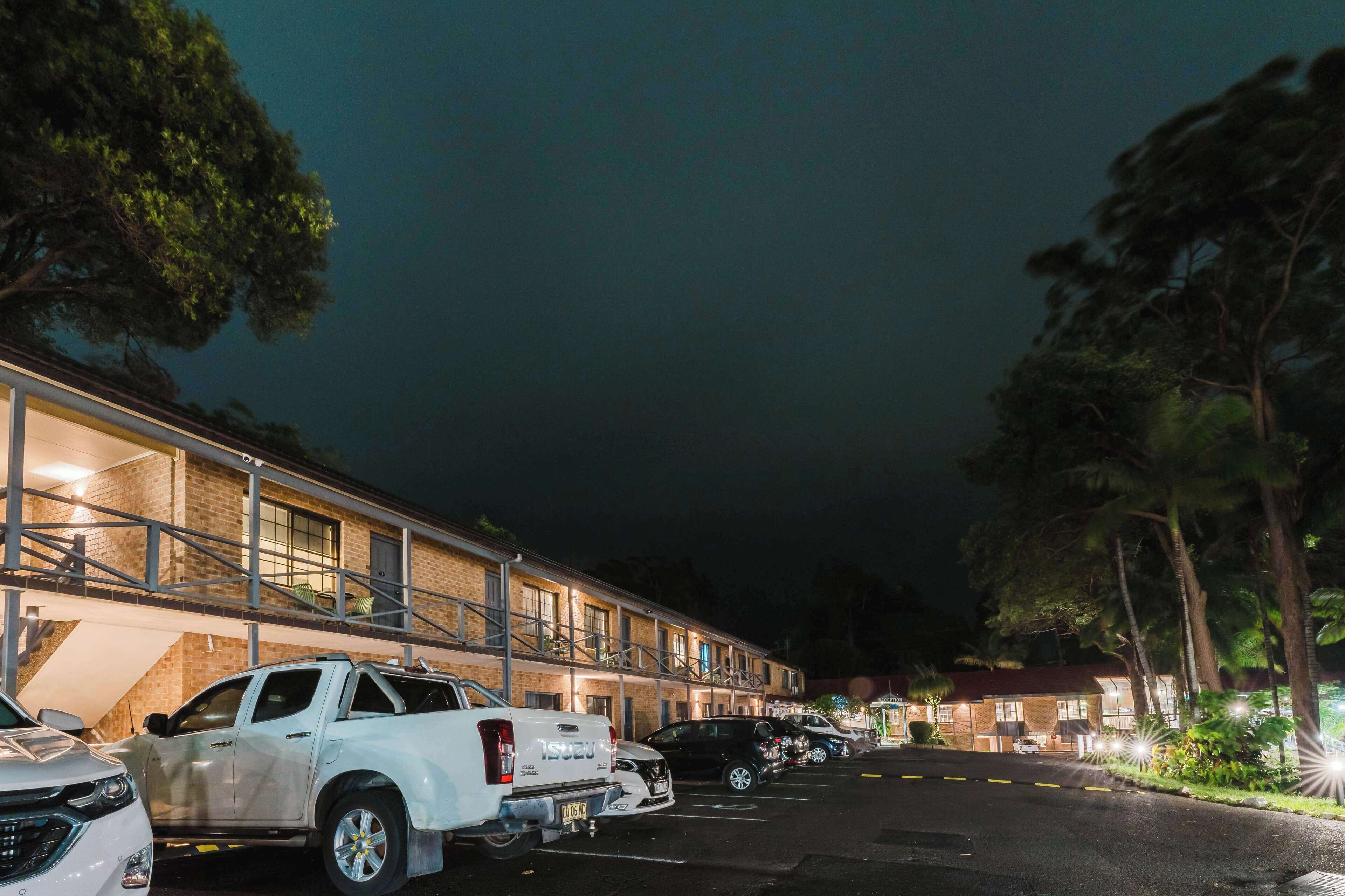 Un motel con múltiples espacios de estacionamiento y un edificio de ladrillo con balcón.