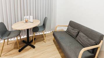 A modern room with a round wooden table, two grey chairs, and a grey sofa.
