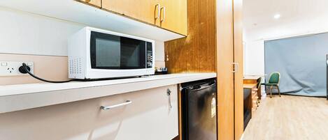 A kitchen with wooden cabinets, a white countertop, a microwave, a dishwasher, and a small table with a chair.