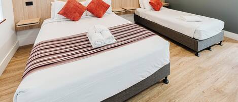 A hotel room with two beds, a striped blanket, and red pillows.