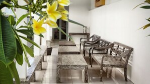 A hallway with a bench, a wooden bench, and a door. - Patrisia Hotel Bali (Denpasar)