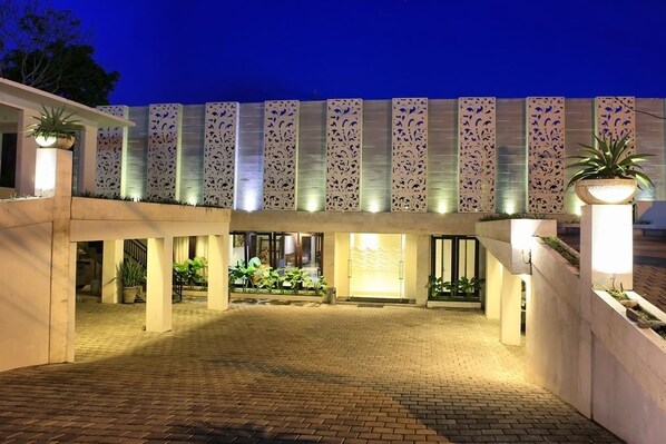 L’entrée d’un hôtel, dotée d’un espace extérieur abrité, de panneaux décoratifs et de plantes en pot.