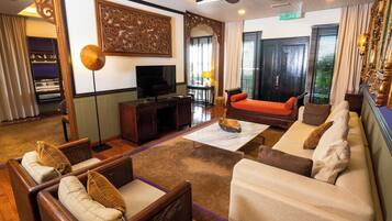 A spacious living area with a sofa, armchairs, a coffee table, and a television.