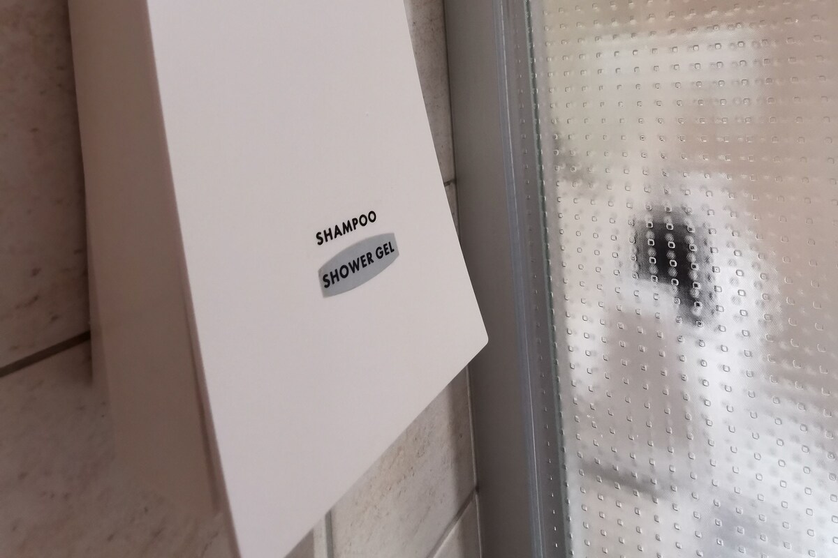 Una caja blanca con la etiqueta 'SHAMPOO SHOWER GEL' sobre un piso de baldosas.