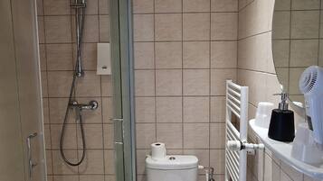 Un baño moderno con cabina de ducha de vidrio, inodoro blanco, lavabo y espejo.
