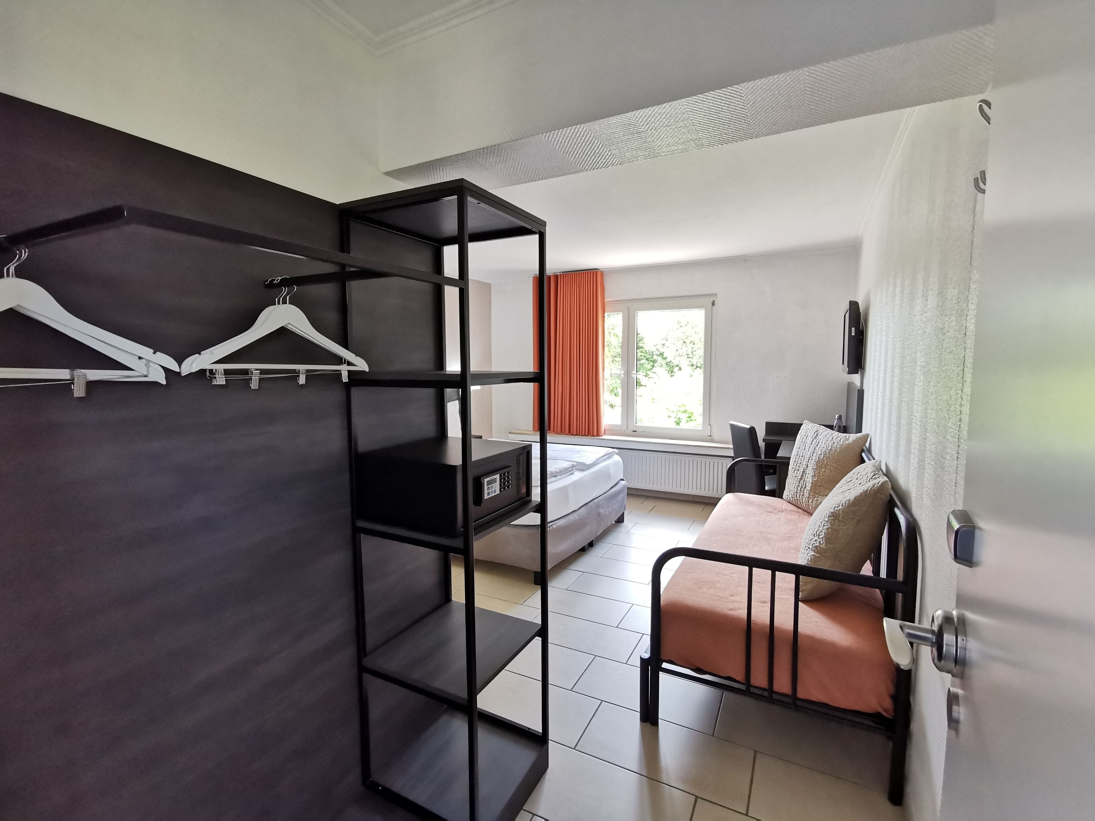 A room with a bed, a desk, a wardrobe, and a window with curtains.