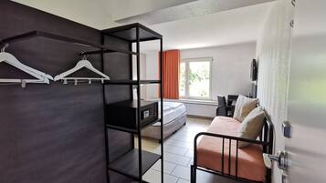 A room with a bed, a desk, a wardrobe, and a window with curtains.