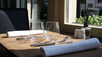 A neatly set dining table with two wine glasses, cutlery, and a rolled napkin.