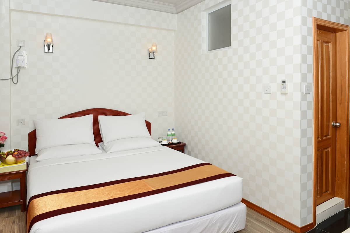 Hotelkamer met een groot bed, twee nachtkastjes, een houten deur en een geruit patroon op de muur.