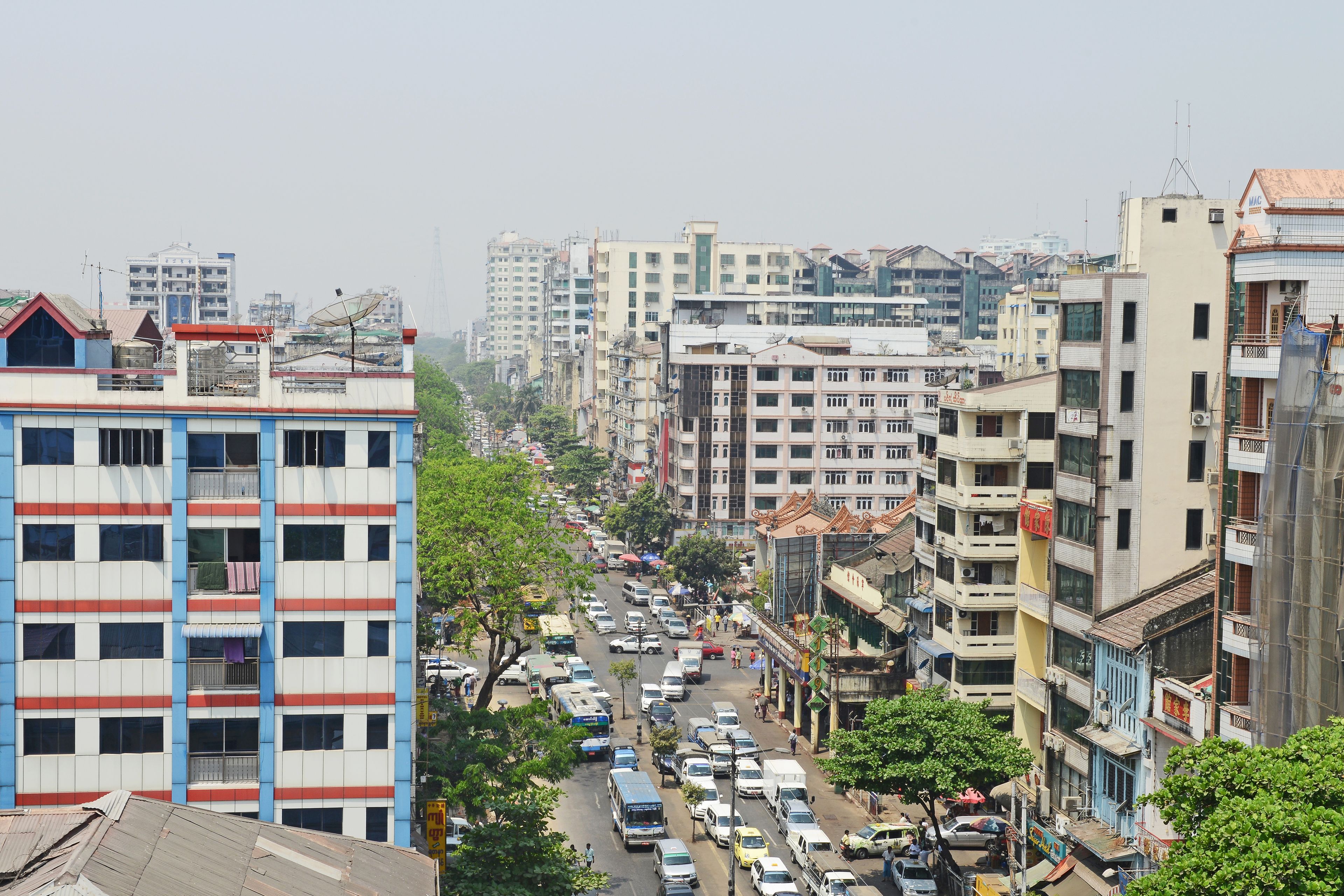 A multi-story building with a grid-like facade, a central courtyard, and a busy street with vehicles and pedestrians.