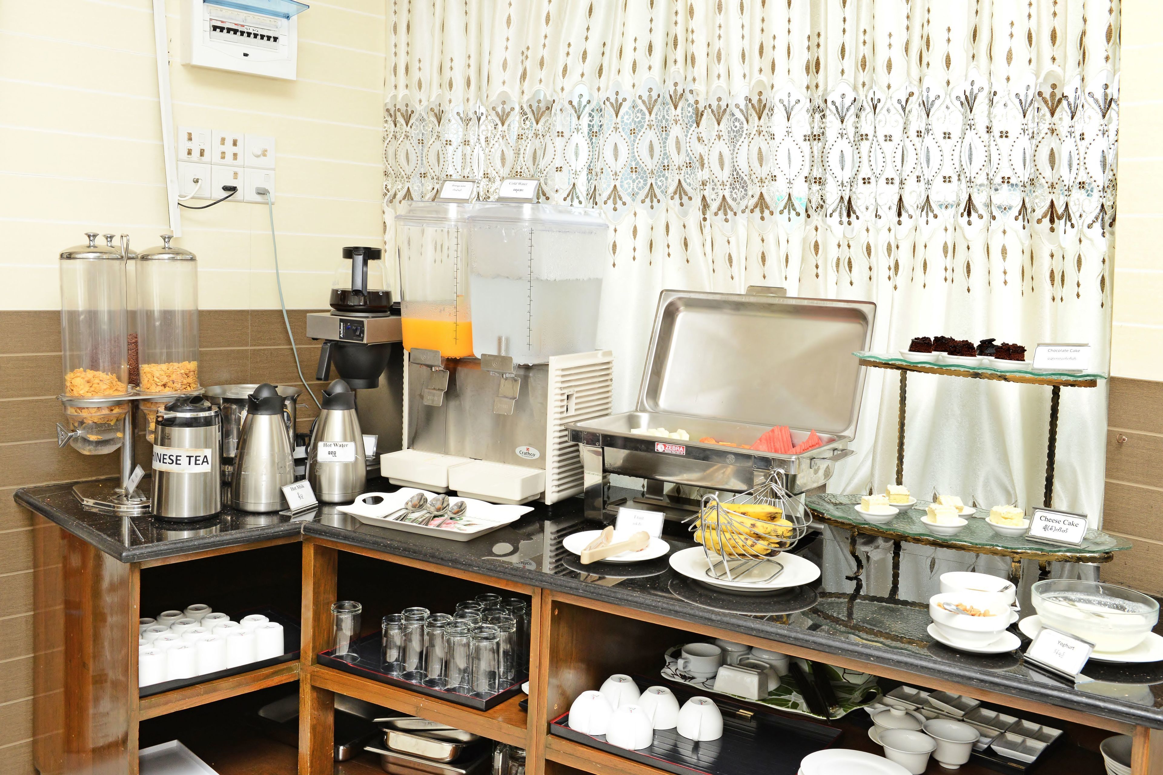 A breakfast buffet with various food items, coffee machines, and tea dispensers.