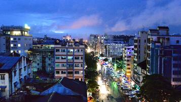 A cityscape at dusk with buildings, a busy street, and a visible rainbow.