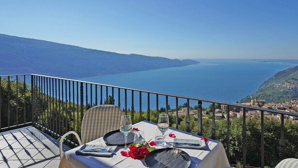 A table set for two with a view of a lake and a hillside town.