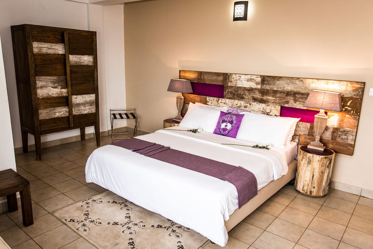 A bedroom with a large bed, a wooden headboard, a nightstand, a lamp, and a small table.