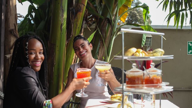 Two people sitting at an outdoor table with a dessert display and drinks. - The Swiss Hotel (Freetown)