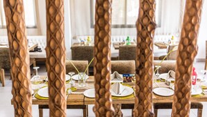 A dining area with wooden tables set for a meal, chairs, and a buffet table in the background. - The Swiss Hotel (Freetown)