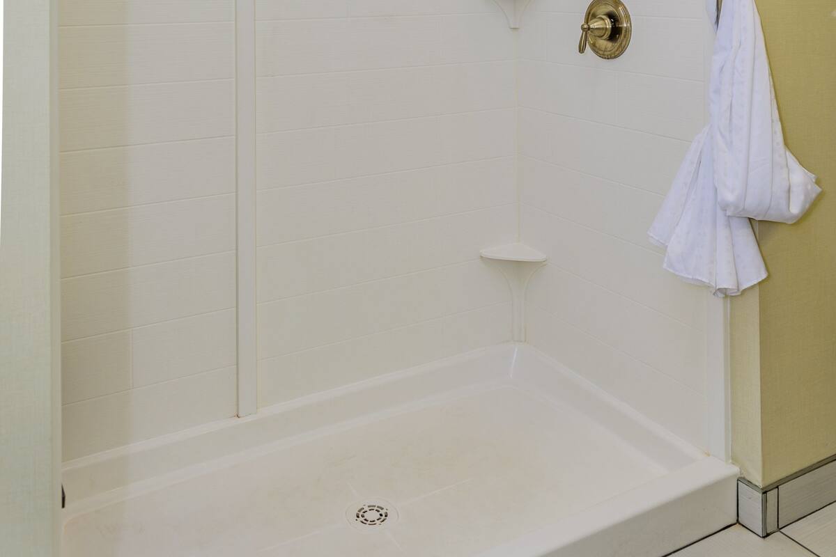 A walk-in shower with a glass door, a towel rack, and a showerhead.