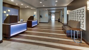 Un vestíbulo de hotel con mostrador de recepción, zona de estar y un largo pasillo.