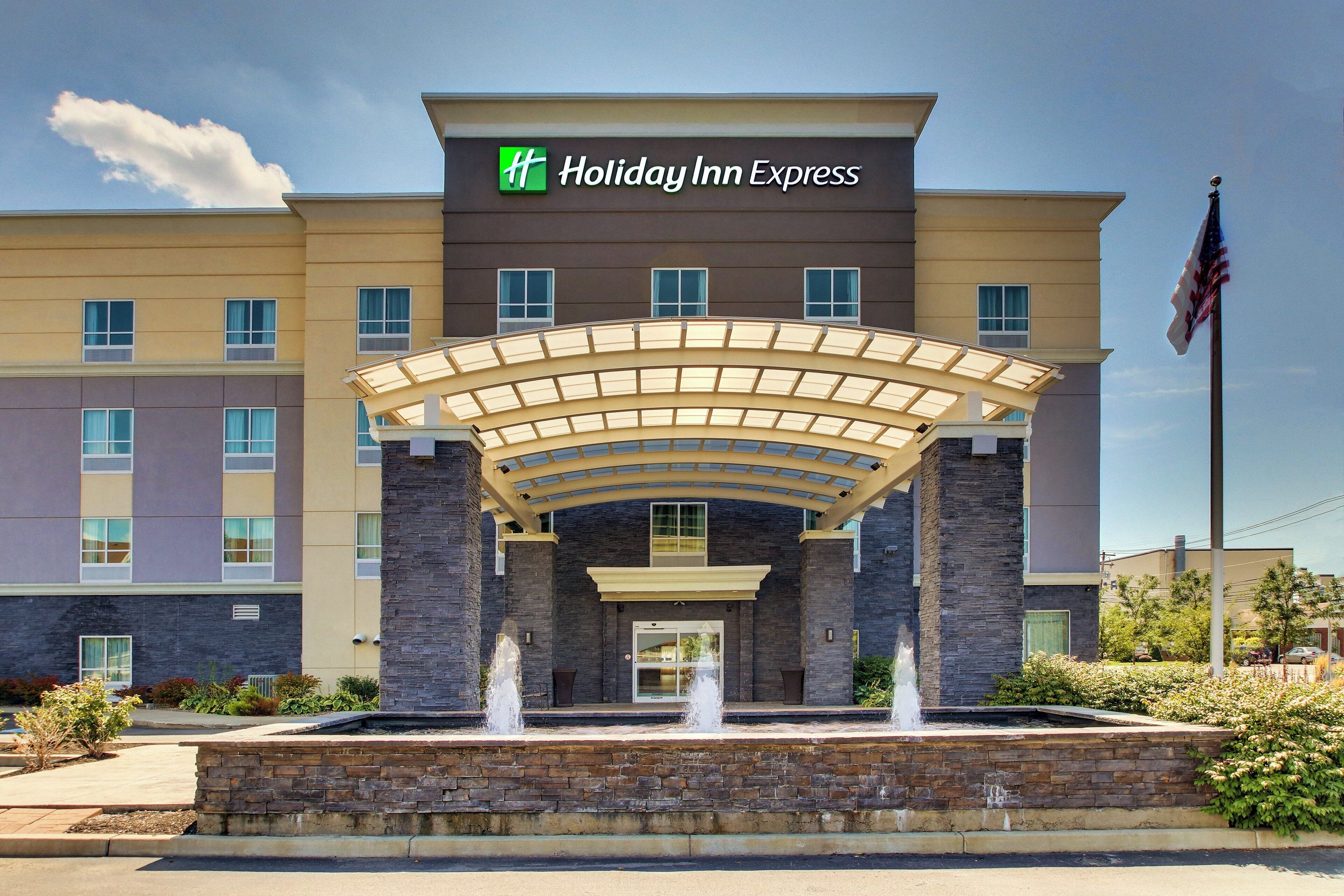 A Holiday Inn Express hotel with a covered entrance, a fountain, and a flag.
