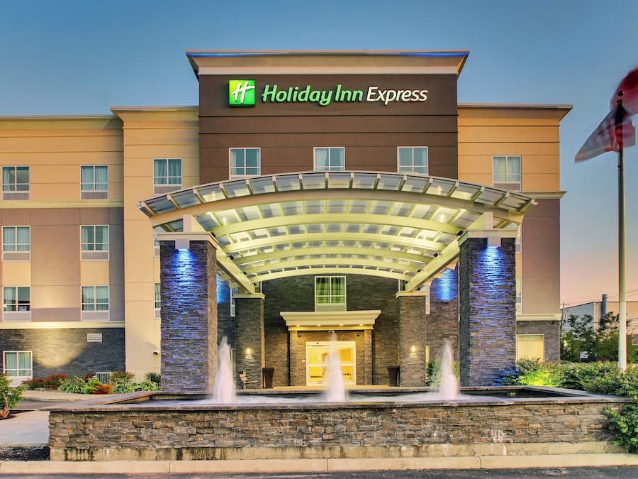 Een Holiday Inn Express hotel met een overdekte ingang, een fontein en een vlag.