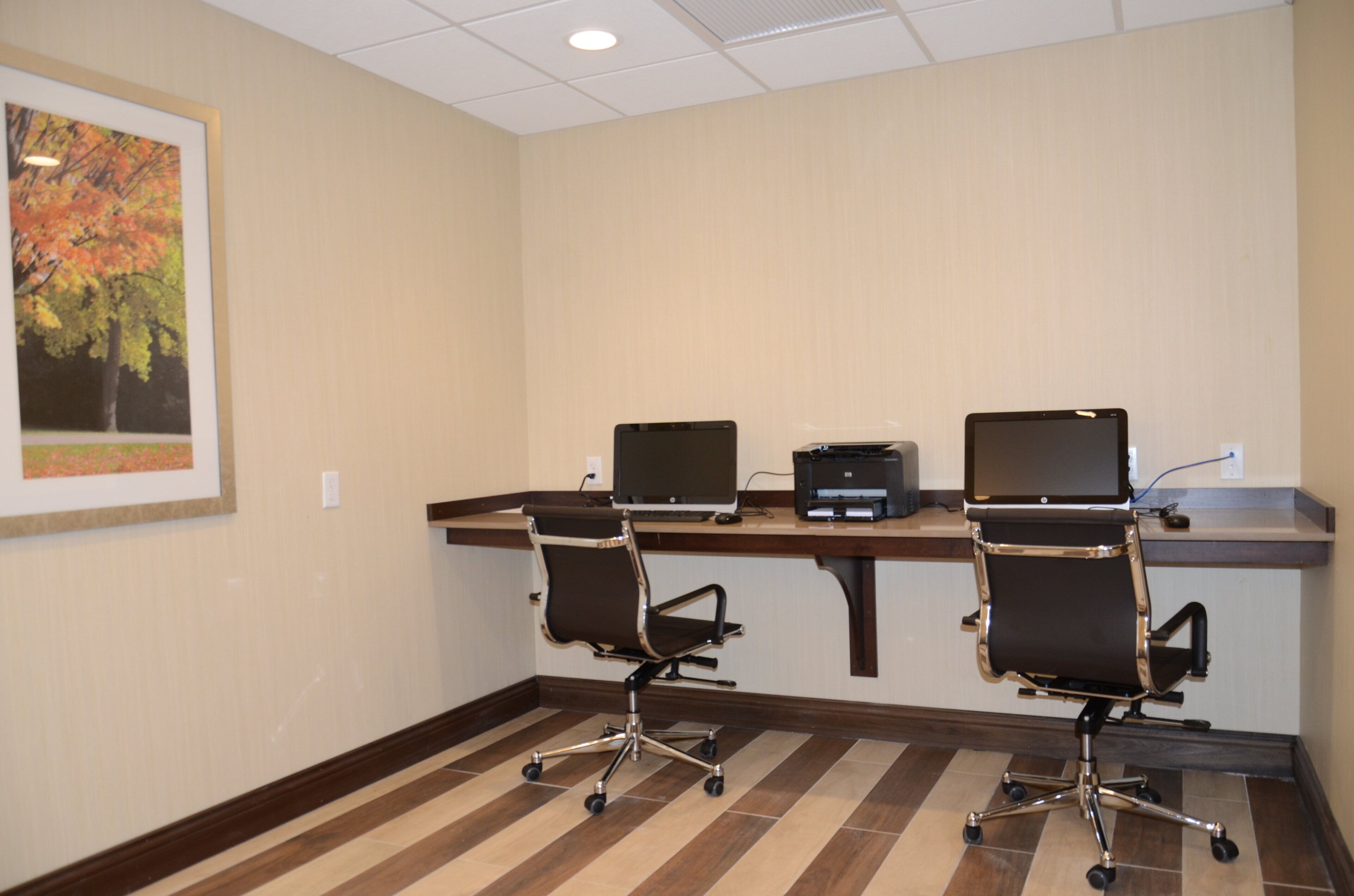 A conference room with two office chairs, a desk, a printer, and a computer monitor.